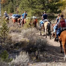 a group of people riding horseback through the mountains