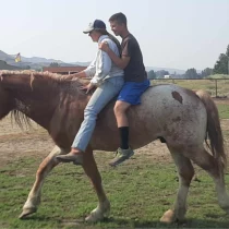 a young lady and a young man riding a horse bareback